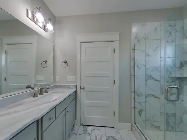 a bathroom with a granite countertop sink a mirror and a shower