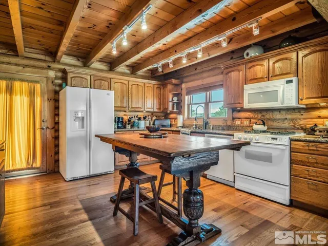 a kitchen with stainless steel appliances granite countertop a table chairs stove and refrigerator