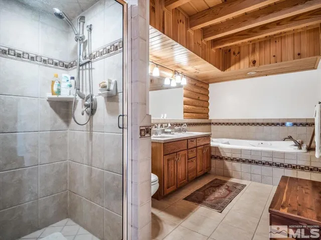 a bathroom with a granite countertop double vanity and a shower
