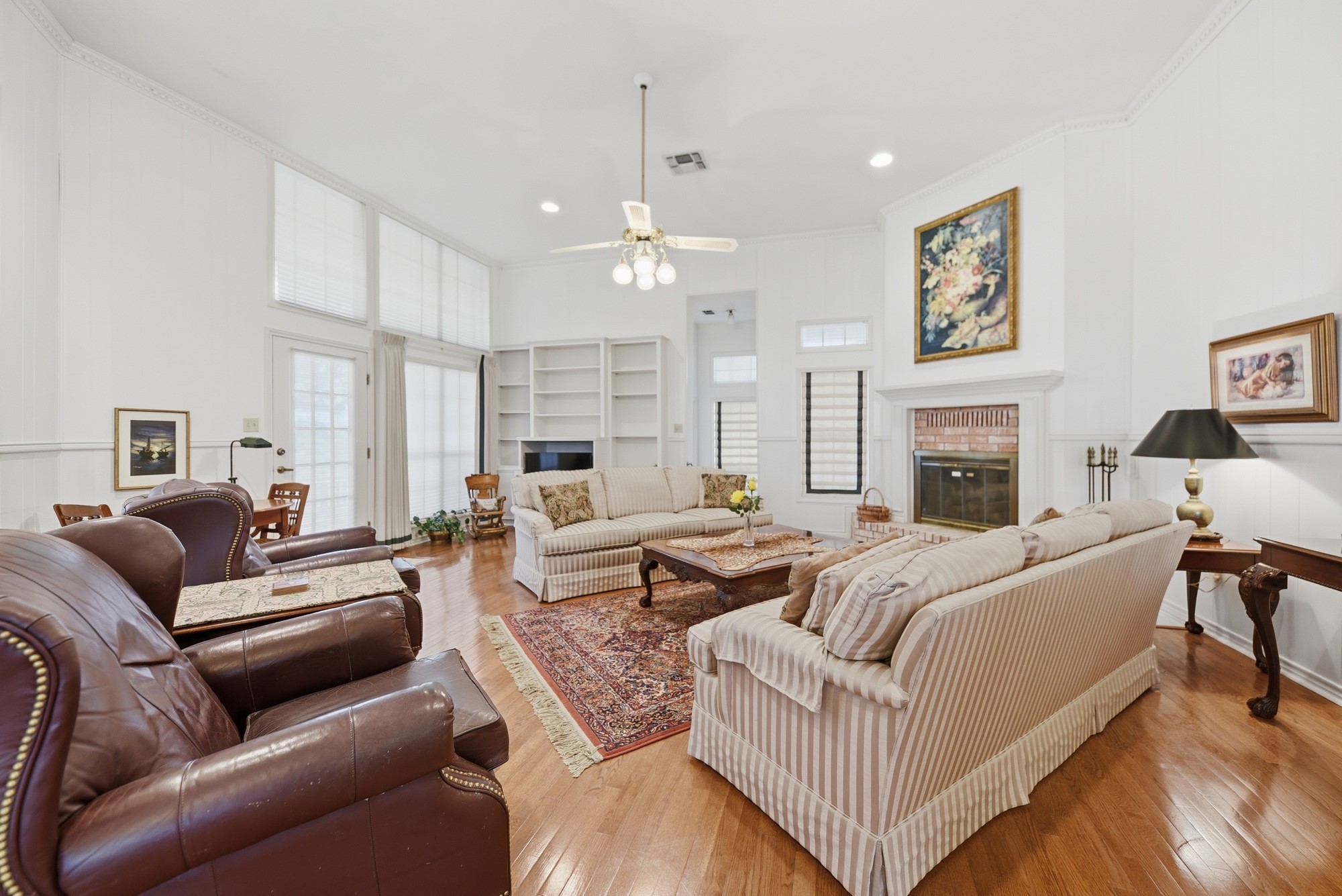 1552 Holub Road Schulenburg, TX 78956 - Photo 16 of 35 A naturally illuminated living room presents high ceilings, built-in features, and a traditional fireplace, all resting on polished hardwood flooring.