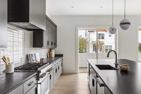 a kitchen with stainless steel appliances a stove a sink a counter space and a window