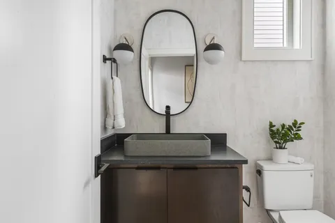 a close view of a sink a mirror and a potted plant on a table