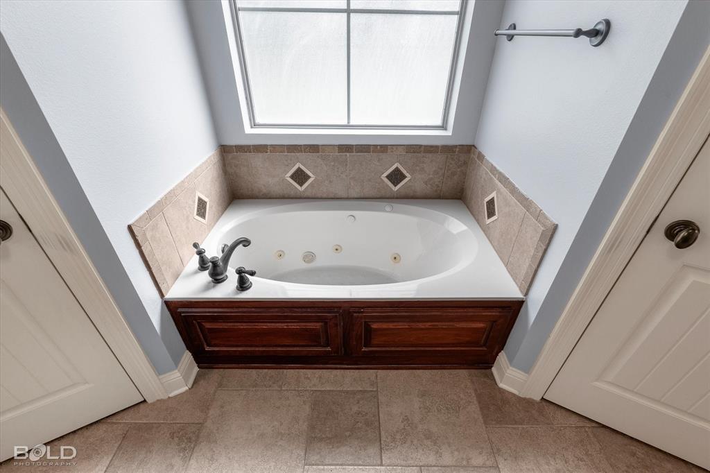 2220 Forest Hills Boulevard Haughton, LA 71037 - Photo 31 of 40 White built-in jetted tub with dark bronze fixtures and a wood-finish cabinet surround