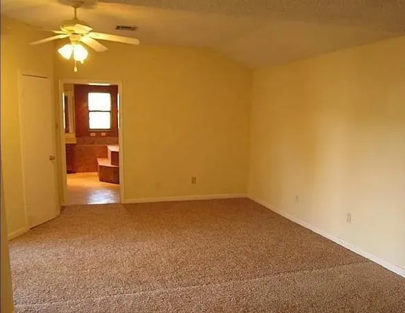 an empty room with a windows and chandelier fan