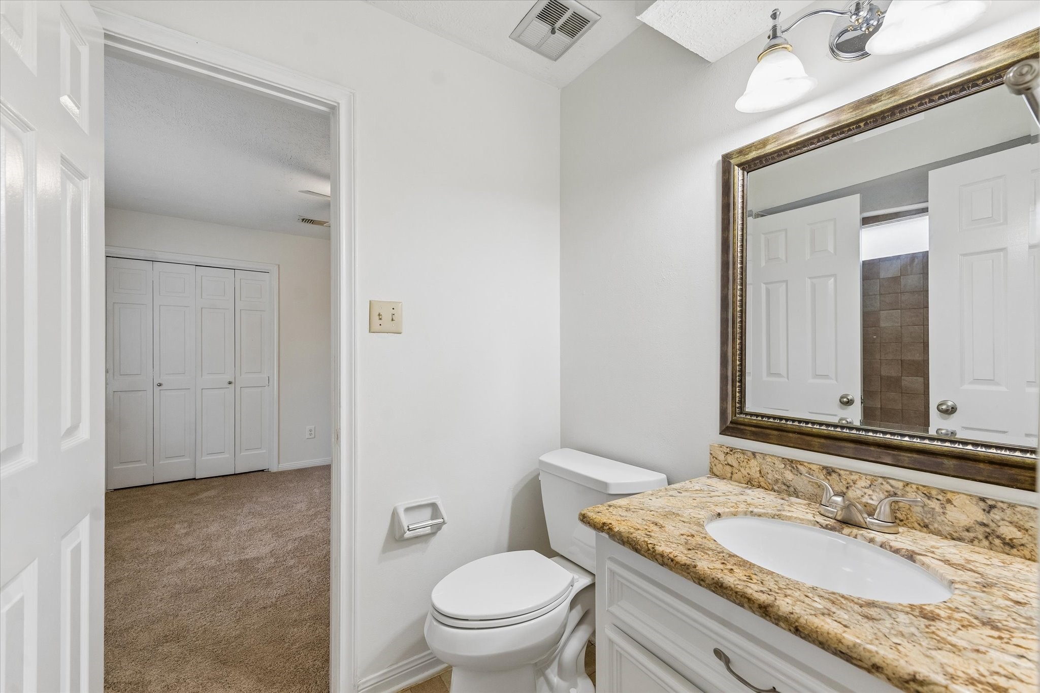 17902 Fernbluff Drive Spring, TX 77379 - Photo 22 of 29 a bathroom with a granite countertop sink a toilet and a mirror