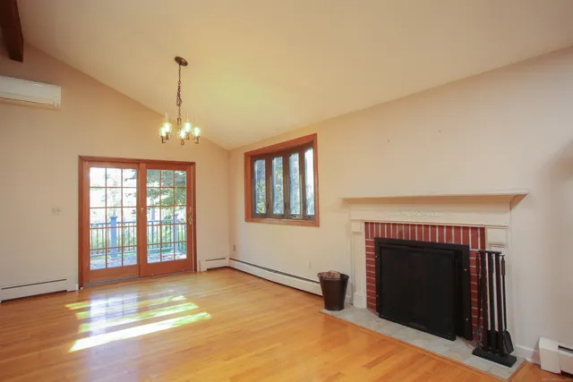 a view of an empty room with window and wooden floor