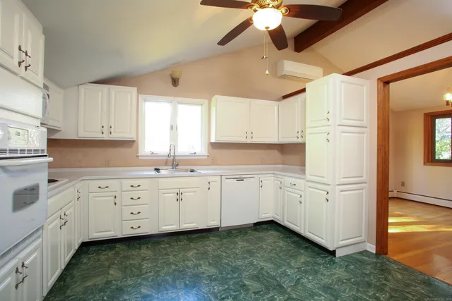 a kitchen with granite countertop white cabinets white appliances with a sink and dishwasher