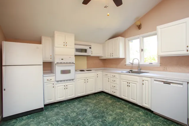 a kitchen that has a lot of white cabinets and a sink