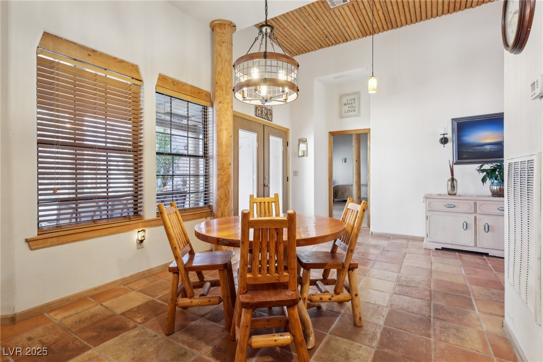 519 North Racetrack Road Henderson, NV 89015 - Photo 30 of 98 Dining space with french doors, stone tile flooring, a high ceiling, a chandelier, and baseboards
