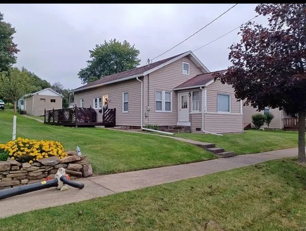 a front view of a house with a garden and trees