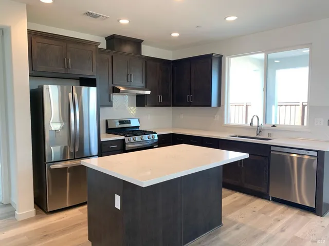 a kitchen with stainless steel appliances granite countertop a refrigerator a sink a stove a microwave and wooden cabinets