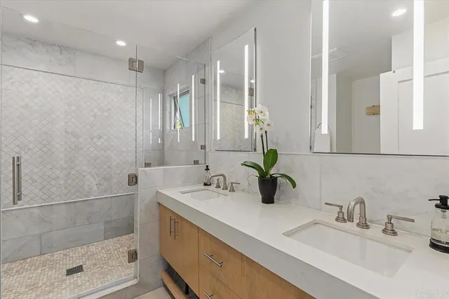 a bathroom with double vanity sinks and a shower