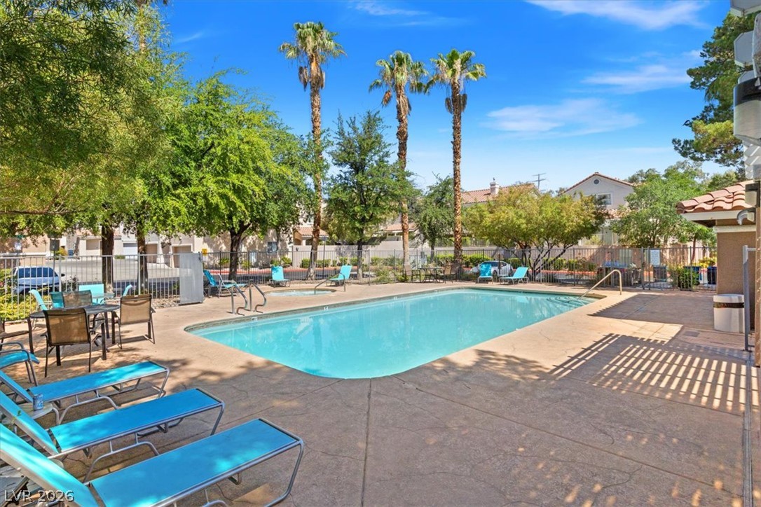 1412 Beaver Spring Street Las Vegas, NV 89128 - Photo 19 of 20 Relax poolside with resort-style living, surrounded by lush greenery and towering palms.