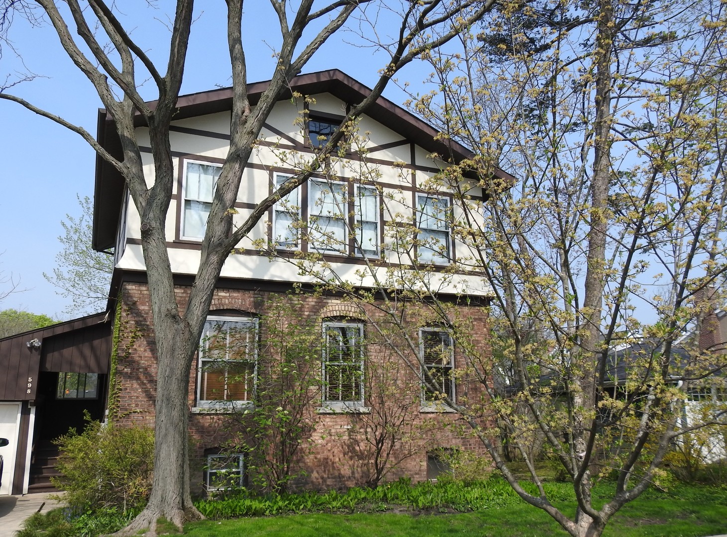 a view of a brick house with large windows and a yard