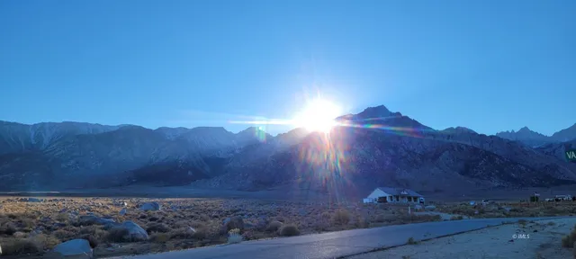 a view of a mountain with sunset in background