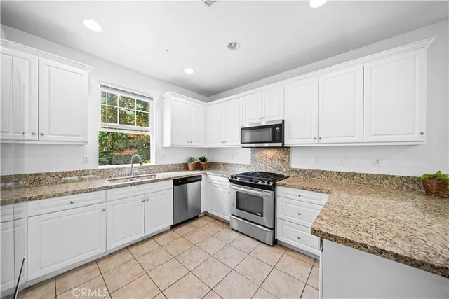 a kitchen with granite countertop white cabinets and white stainless steel appliances