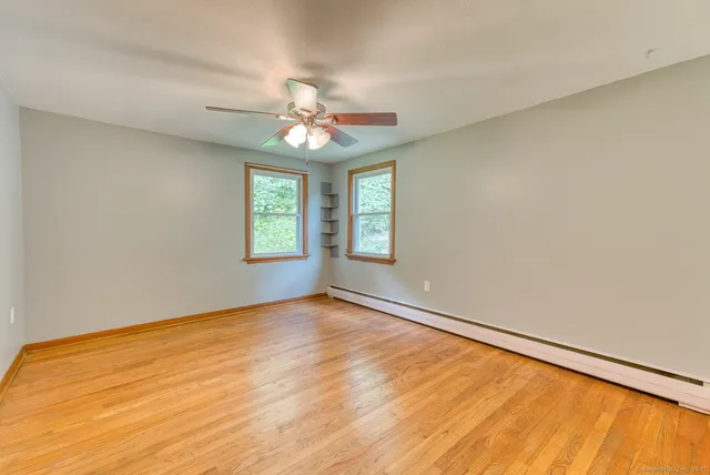 a view of an empty room with wooden floor and a window