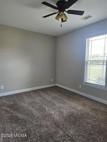 an empty room with a ceiling fan and window