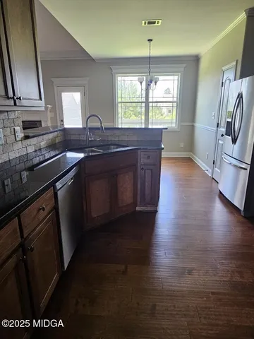 a kitchen with stainless steel appliances granite countertop a stove a sink a refrigerator and wooden floor