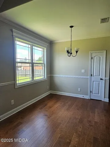 an empty room with wooden floor cabinet and windows