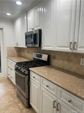 a kitchen with granite countertop white cabinets and stainless steel appliances