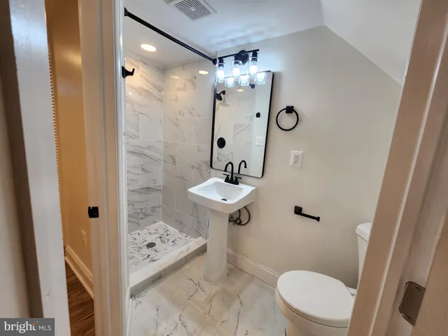 a bathroom with a sink a toilet a mirror and shower