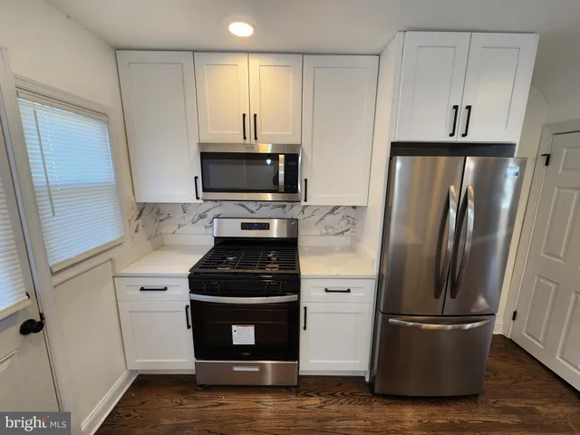 a kitchen with a refrigerator stove and white cabinets
