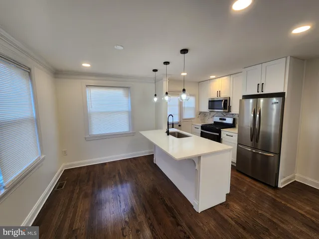 a kitchen with stainless steel appliances a refrigerator a stove a sink cabinets and wooden floor