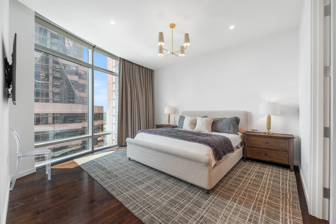 200 Congress Avenue, Unit 19F Austin, TX 78701 - Photo 18 of 40 a spacious bedroom with a large bed and a chandelier