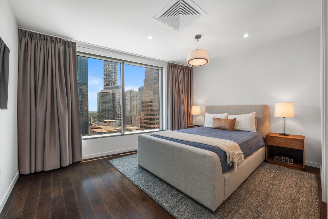 200 Congress Avenue, Unit 19F Austin, TX 78701 - Photo 23 of 40 a spacious bedroom with a large bed and a chandelier
