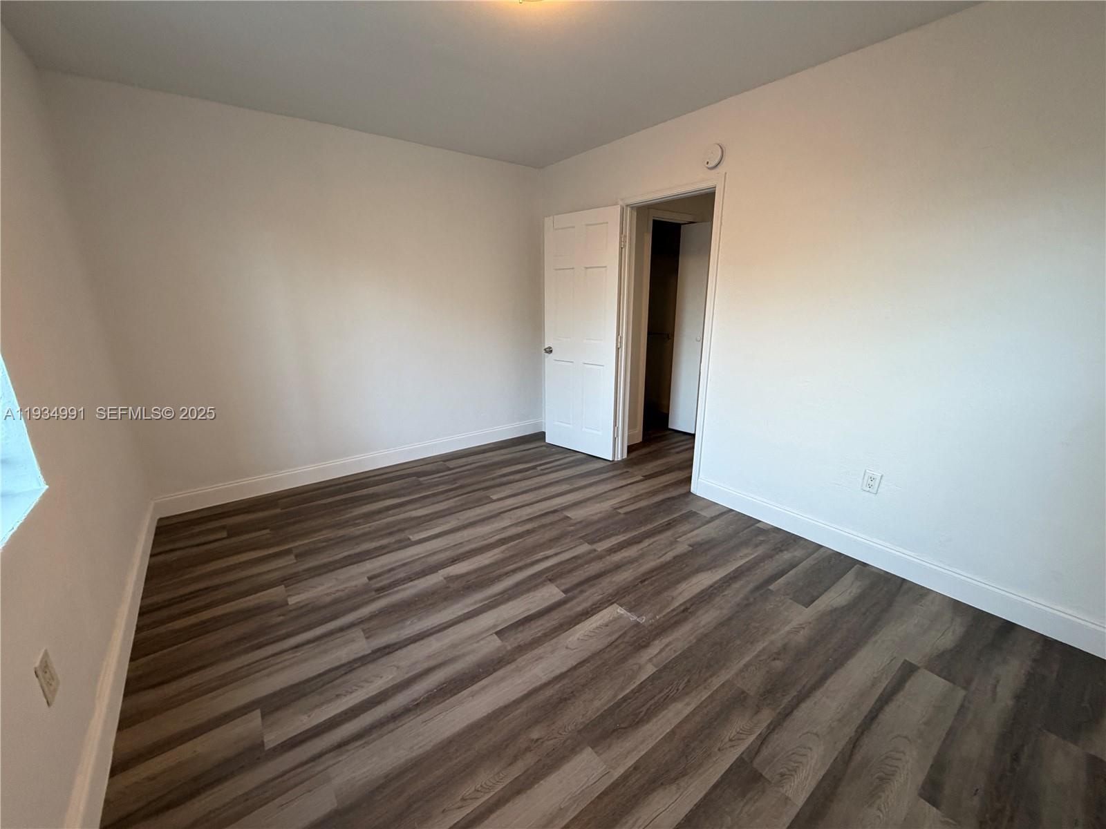7928 Harding Avenue, Unit 1 Miami Beach, FL 33141 - Photo 12 of 12 a view of an empty room with wooden floor and a window