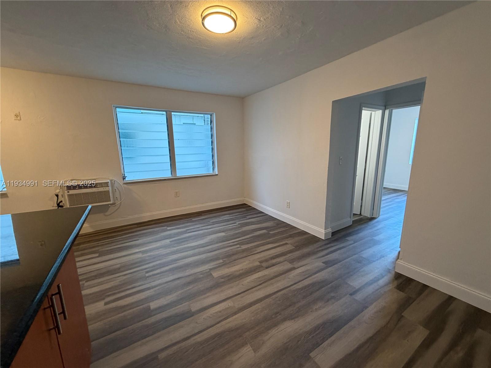 7928 Harding Avenue, Unit 1 Miami Beach, FL 33141 - Photo 3 of 12 a view of an empty room with wooden floor and a window