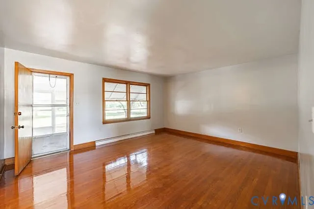 an empty room with wooden floor and windows