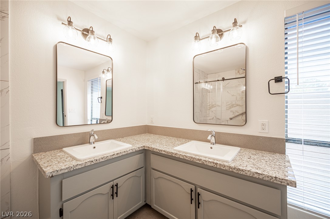 7041 North Decatur Boulevard Las Vegas, NV 89131 - Photo 18 of 33 Dual vanities with granite counters provide ample space in this well-appointed bathroom.