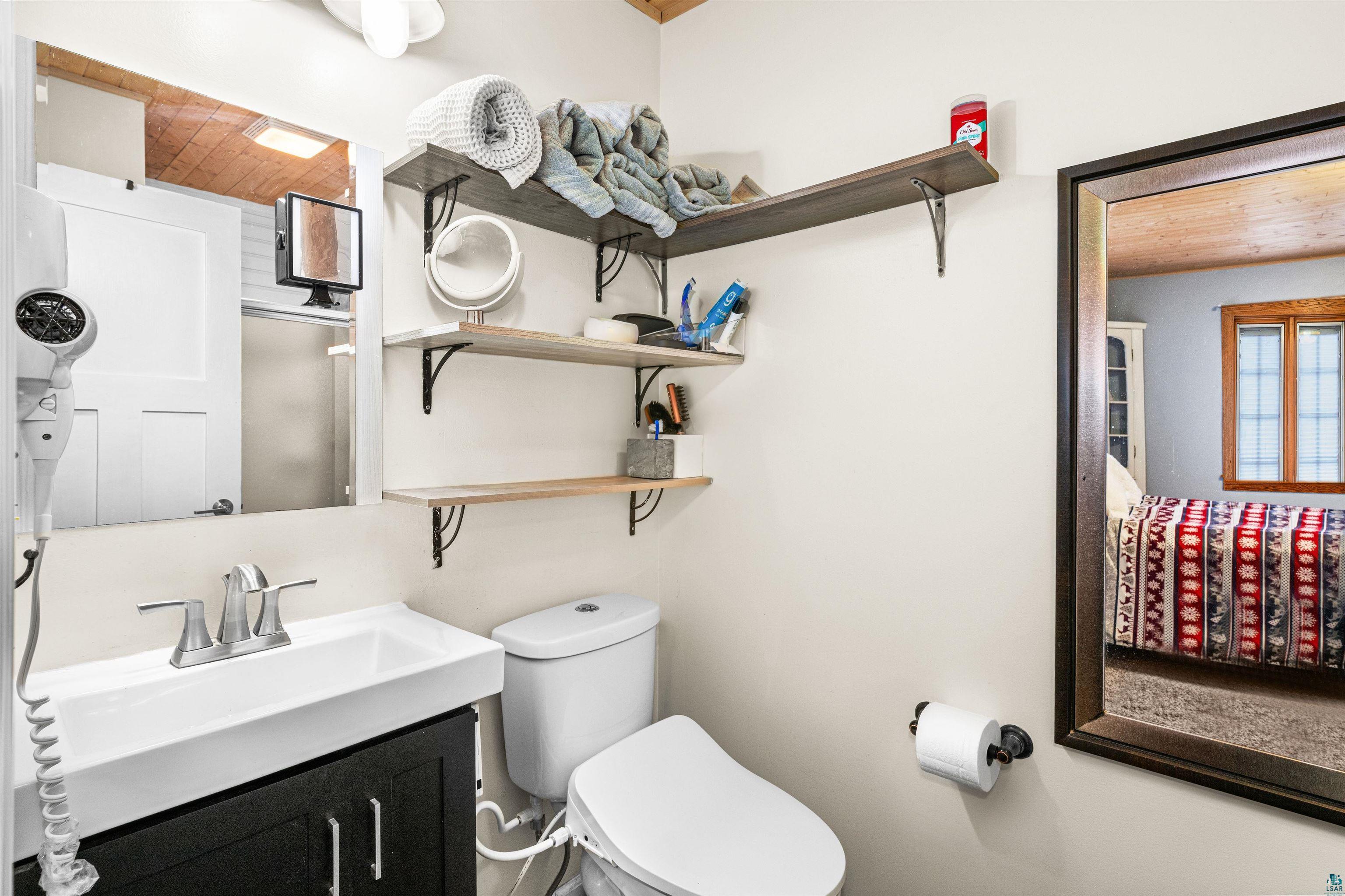 3325 Strand Road Duluth, MN 55803 - Photo 16 of 25 Bathroom featuring a contemporary vanity with a rectangular sink, wall-mounted mirror, and tiered floating shelves for storage