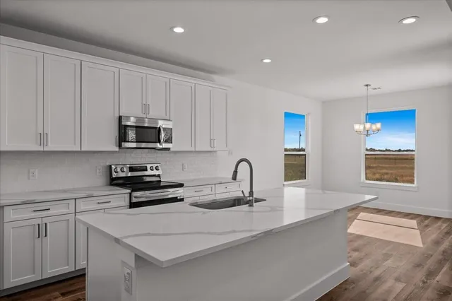 a kitchen with stainless steel appliances granite countertop a sink a stove a microwave a counter space and cabinets