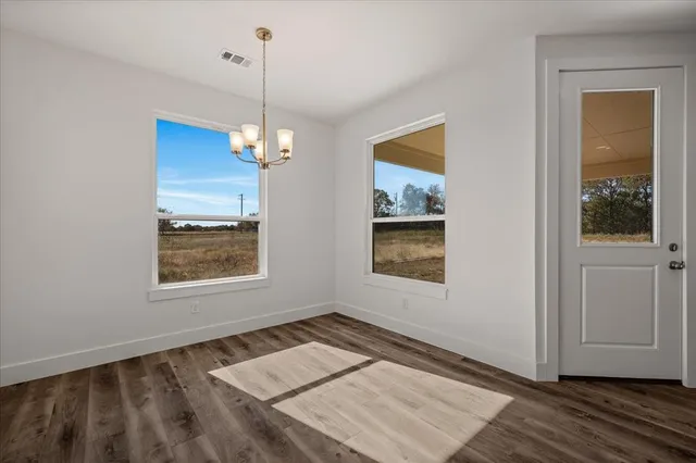 a view of an empty room with window and wooden floor