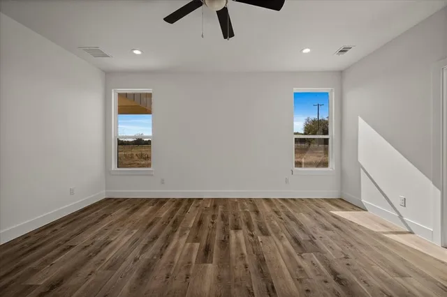 a view of empty room with wooden floor and window