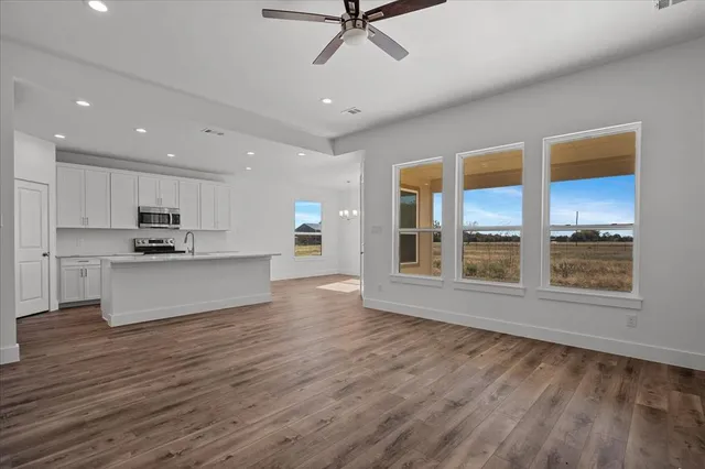 a view of an empty room with a kitchen and wooden floor