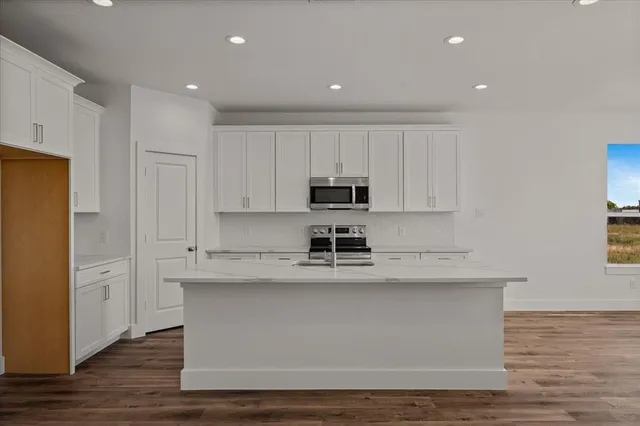 a view of kitchen with stainless steel appliances granite countertop cabinets and wooden floor