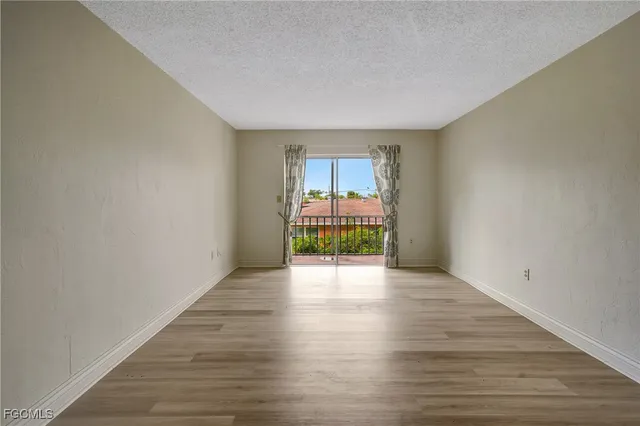 a view of an empty room with wooden floor and closet