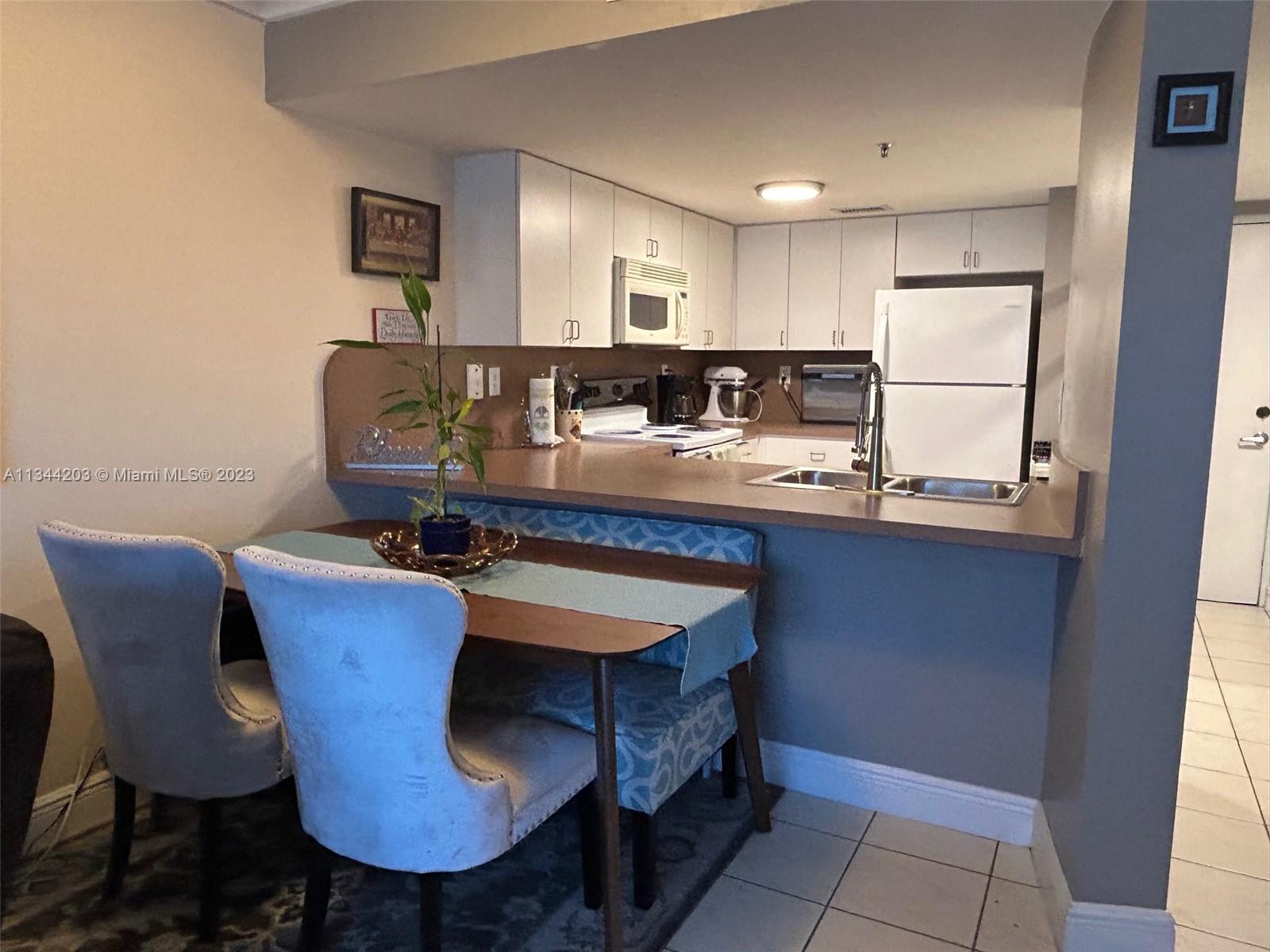 55 East 4th Street, Unit 302 Hialeah, FL 33010 - Photo 6 of 17 a kitchen with a table chairs sink and cabinets