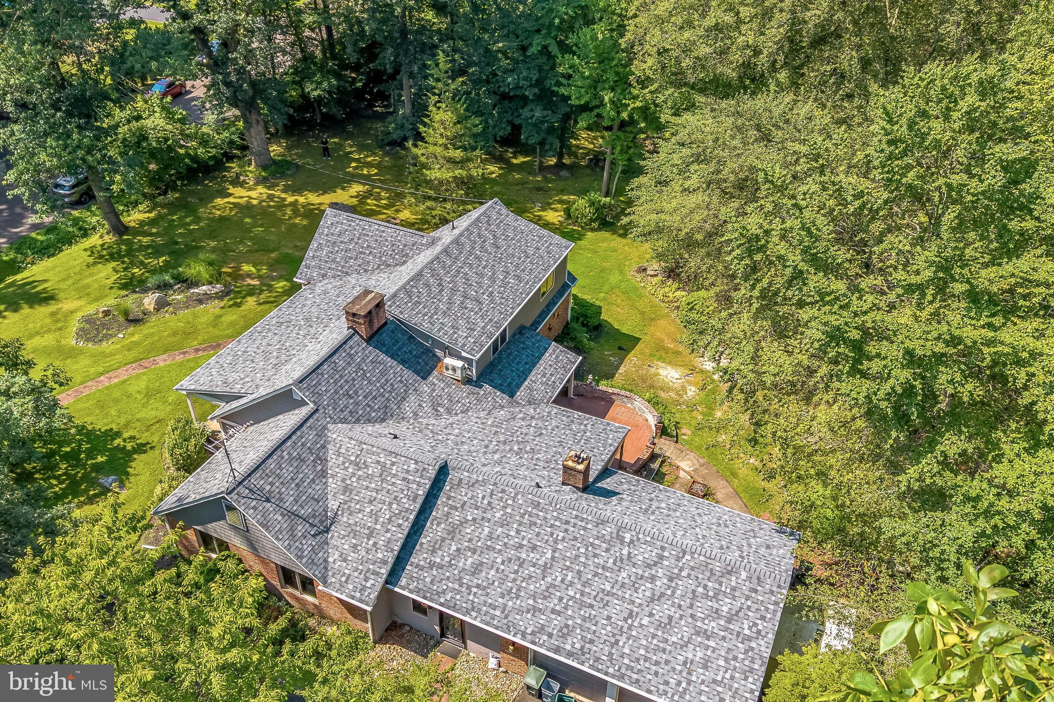 an aerial view of a house with swimming pool and large trees