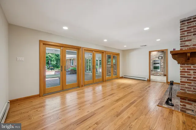 a view of an empty room with wooden floor fireplace and a window