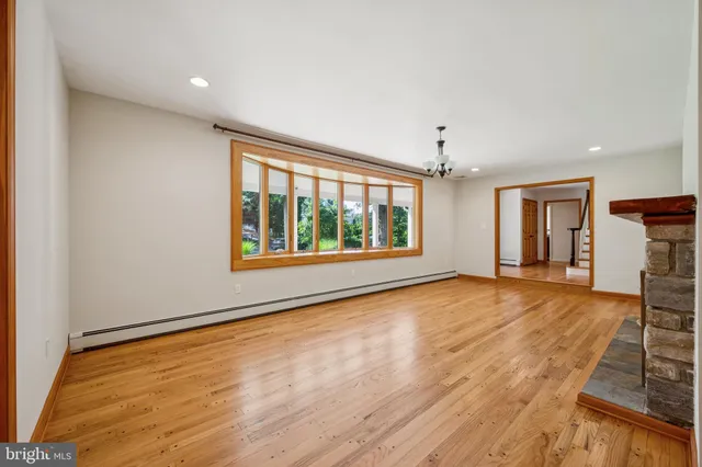a view of an empty room with wooden floor fireplace and a window