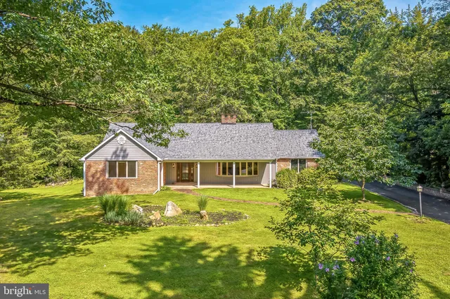a view of a house with a big yard and large trees