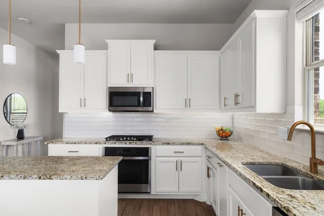 a kitchen with granite countertop a sink a stove and cabinets