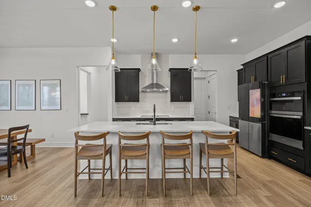 a kitchen with stainless steel appliances kitchen island granite countertop a dining table chairs and sink