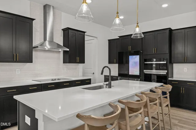 a kitchen with stainless steel appliances a sink a microwave a refrigerator and chairs