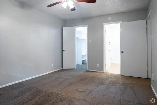 an empty room with a chandelier fan and windows